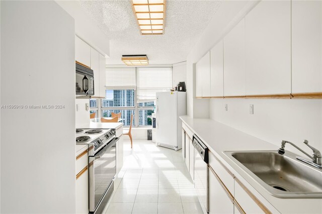 kitchen with white cabinetry, a textured ceiling, white appliances, sink, and light tile floors