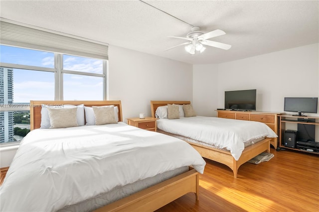 bedroom featuring hardwood / wood-style flooring, ceiling fan, and a textured ceiling