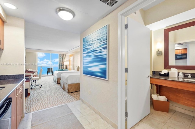 hallway with light colored carpet, sink, and expansive windows