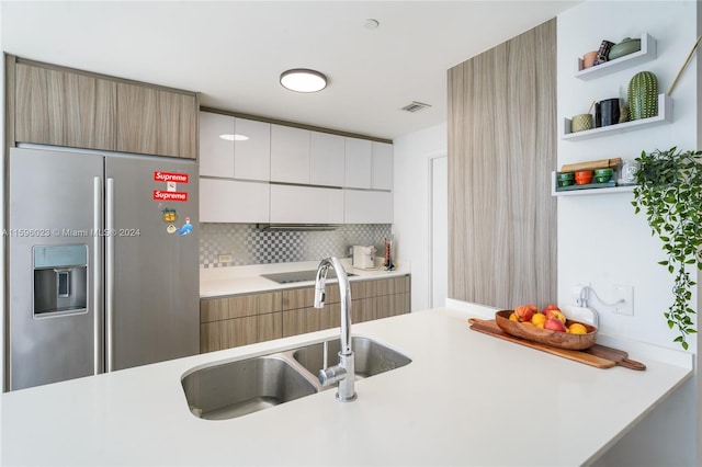 kitchen with tasteful backsplash, stainless steel fridge, sink, and white cabinets