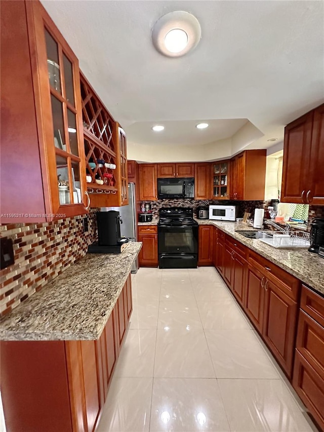 kitchen featuring light stone counters, light tile patterned flooring, black appliances, glass insert cabinets, and tasteful backsplash
