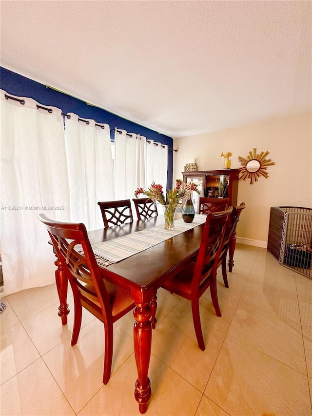 dining space featuring light tile patterned floors, baseboards, and a textured ceiling