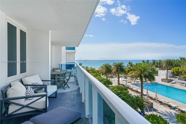 balcony with a water view and a fenced in pool