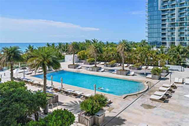 community pool with a patio area and a water view