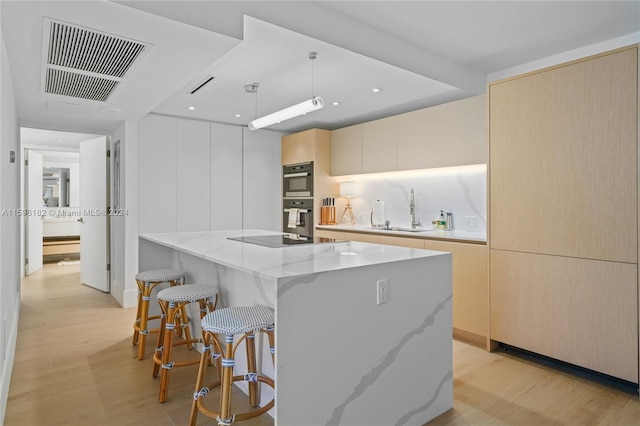 kitchen featuring light stone counters, a kitchen island, a sink, visible vents, and modern cabinets