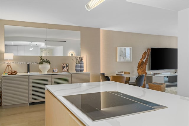 kitchen with modern cabinets, light stone countertops, black electric cooktop, and light wood-style floors