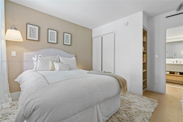 bedroom with a closet, ensuite bathroom, and wood finished floors