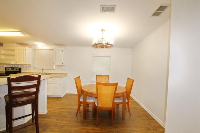 dining room with dark wood-type flooring, sink, and an inviting chandelier