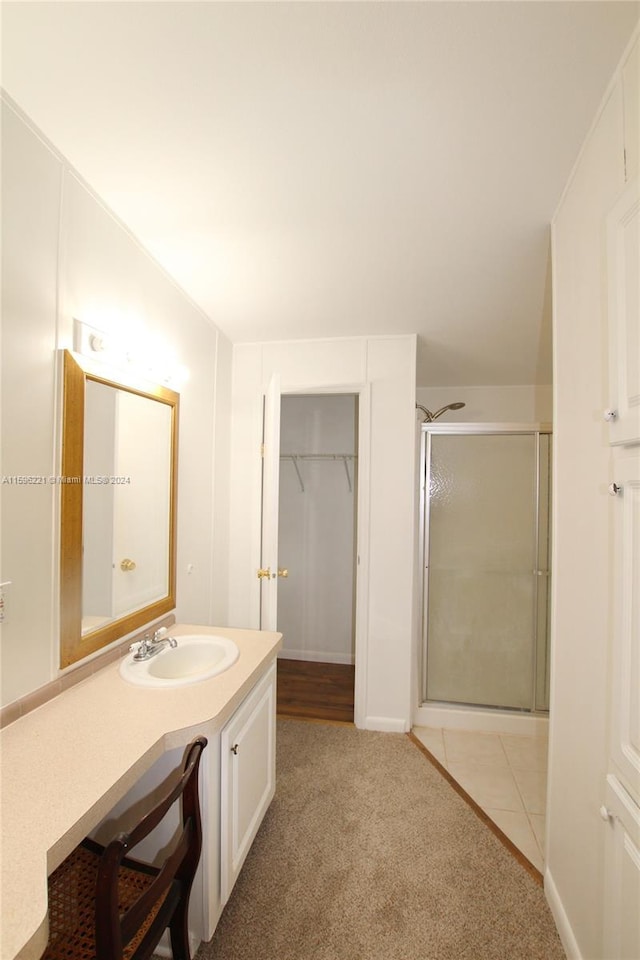 bathroom with tile patterned flooring, vanity, and walk in shower