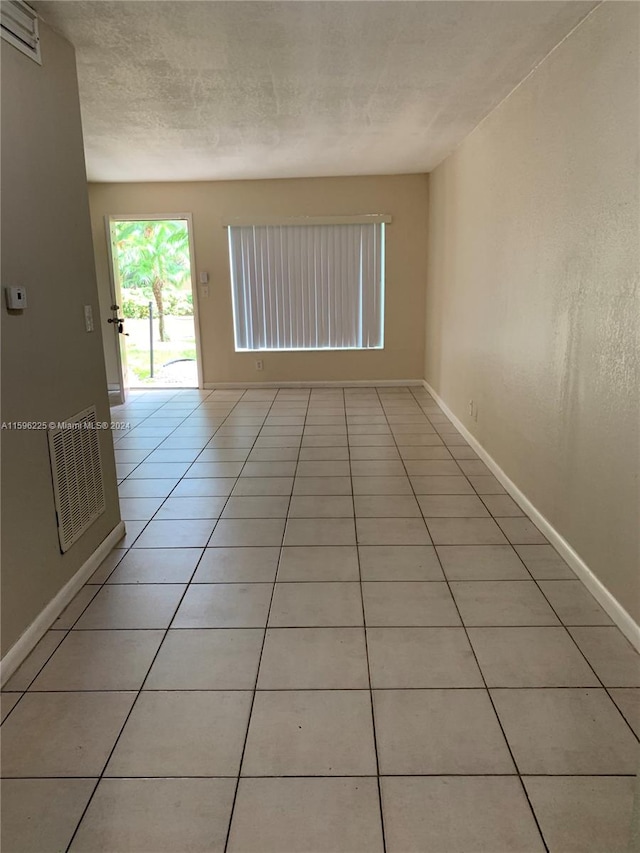 unfurnished room with light tile patterned floors and a textured ceiling