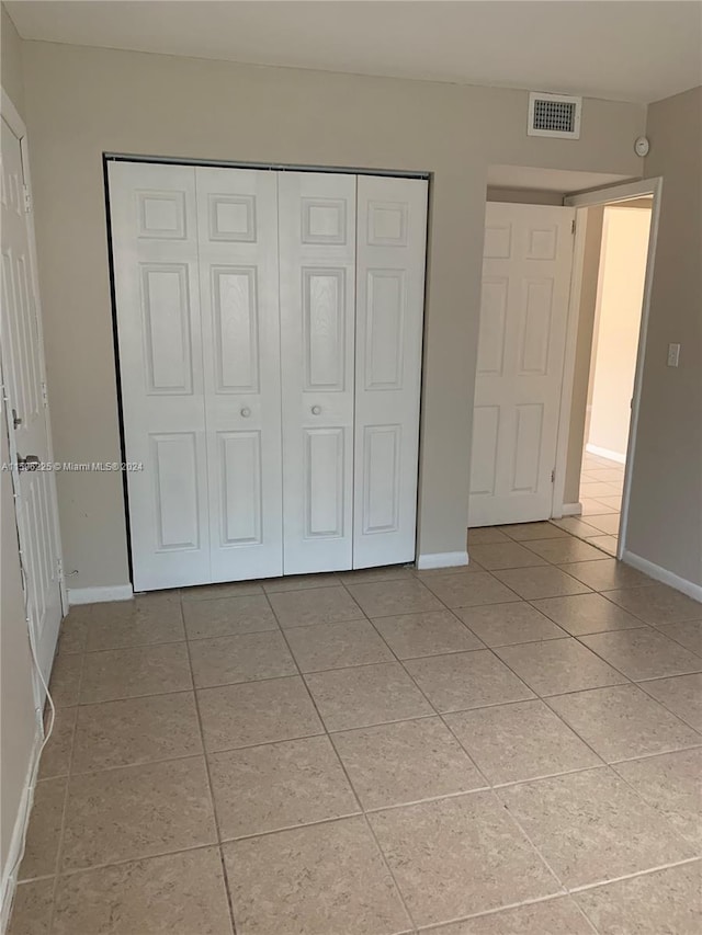 unfurnished bedroom with light tile patterned floors and a closet