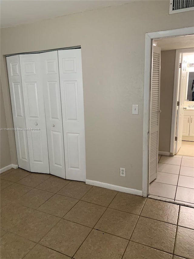 unfurnished bedroom featuring light tile patterned flooring, connected bathroom, and a closet