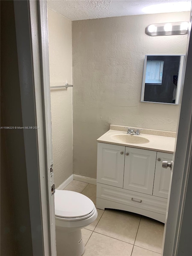 bathroom with tile patterned flooring, vanity, a textured ceiling, and toilet