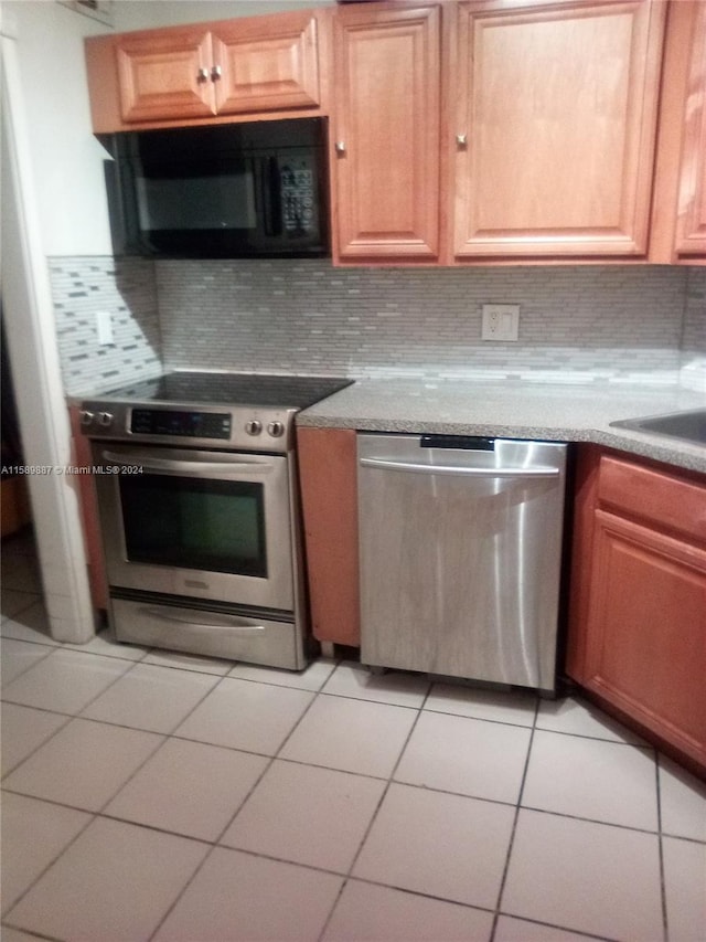 kitchen featuring stainless steel appliances, light tile floors, sink, and backsplash