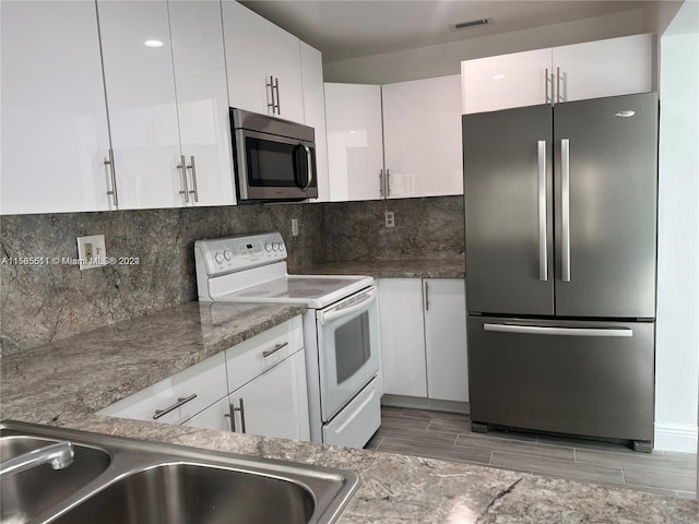 kitchen featuring appliances with stainless steel finishes, backsplash, and white cabinetry