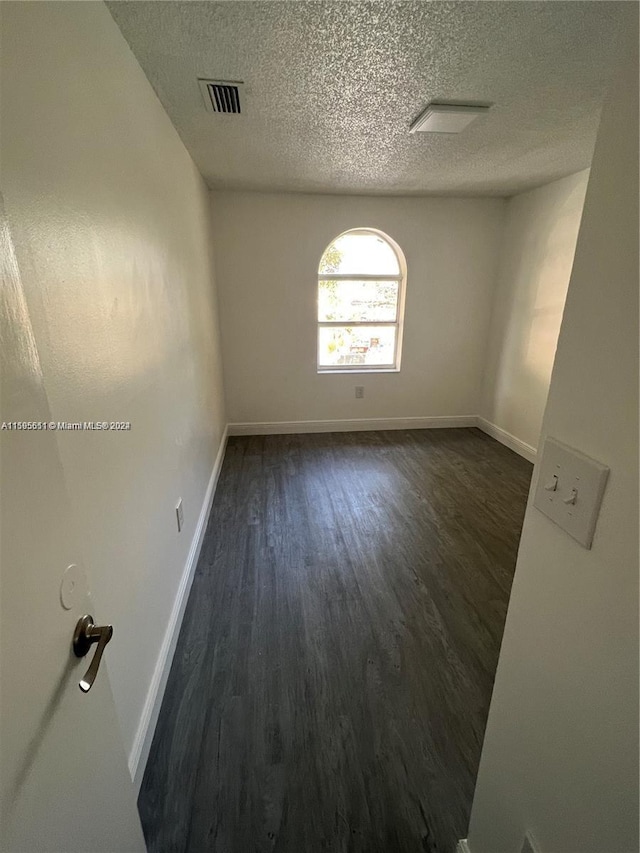 unfurnished room featuring dark hardwood / wood-style flooring and a textured ceiling