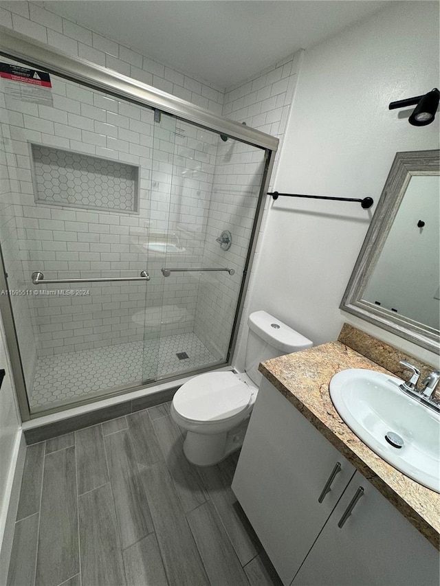 bathroom with an enclosed shower, vanity, and toilet