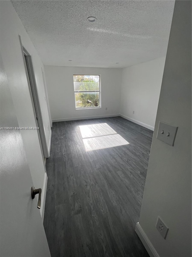 unfurnished room with dark hardwood / wood-style flooring and a textured ceiling