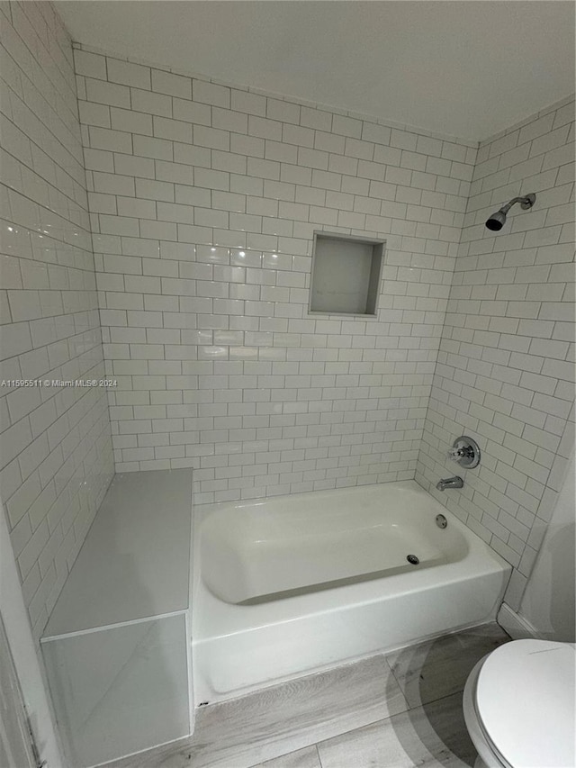 bathroom featuring tiled shower / bath combo and toilet