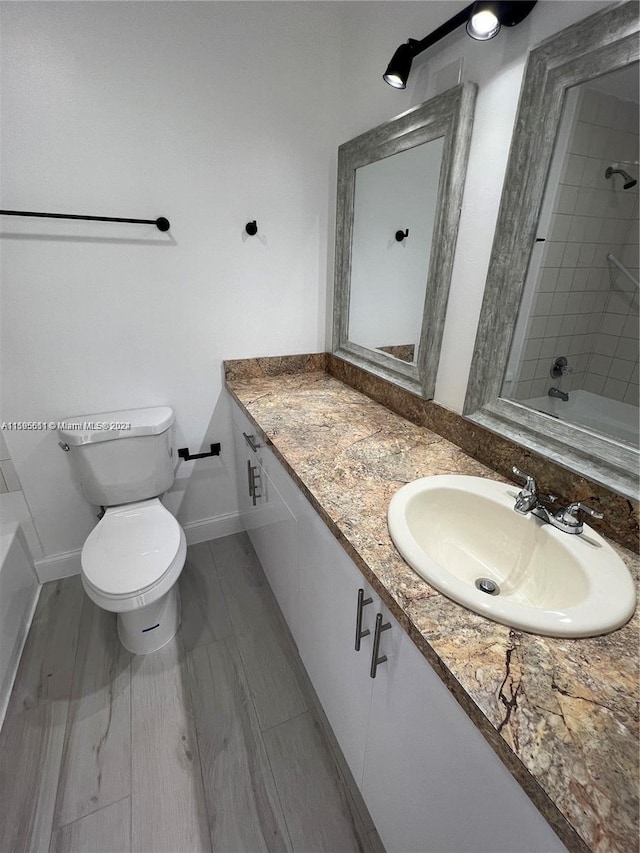 bathroom with wood-type flooring, vanity, and toilet