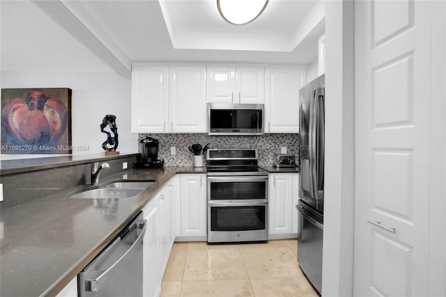 kitchen featuring sink, a tray ceiling, tasteful backsplash, white cabinetry, and stainless steel appliances