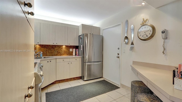 kitchen with stainless steel refrigerator, light tile patterned floors, decorative backsplash, sink, and stove