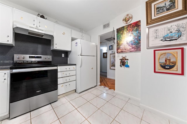 kitchen featuring stainless steel electric range oven, white fridge, backsplash, light tile floors, and white cabinets