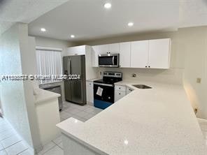 kitchen featuring appliances with stainless steel finishes, white cabinetry, and light tile floors