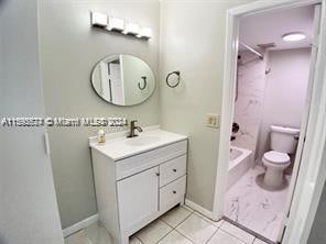 full bathroom featuring shower / bathtub combination, tile floors, toilet, and vanity with extensive cabinet space