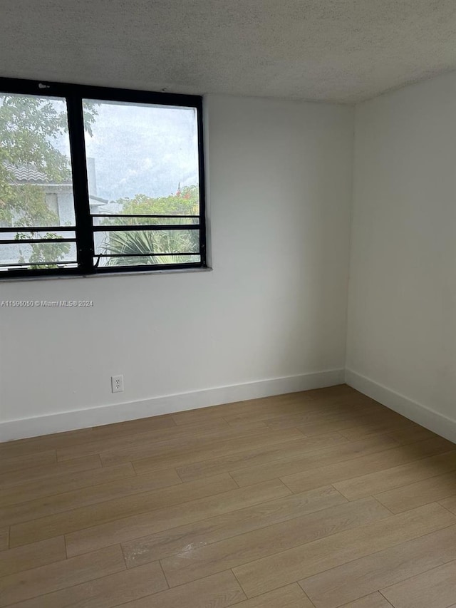 unfurnished room featuring a textured ceiling and light wood-type flooring