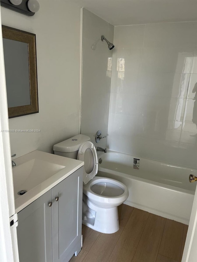 full bathroom with hardwood / wood-style floors, vanity, toilet, and tiled shower / bath