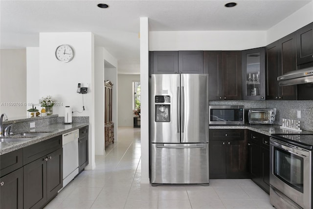 kitchen featuring stone countertops, sink, decorative backsplash, dark brown cabinetry, and stainless steel appliances