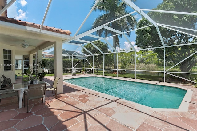 view of swimming pool with ceiling fan, a patio area, and glass enclosure