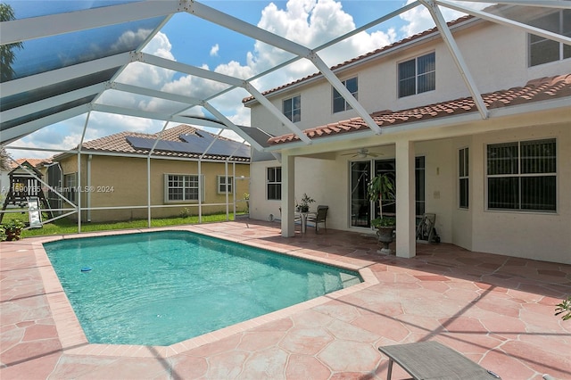 view of pool with a patio, ceiling fan, and glass enclosure