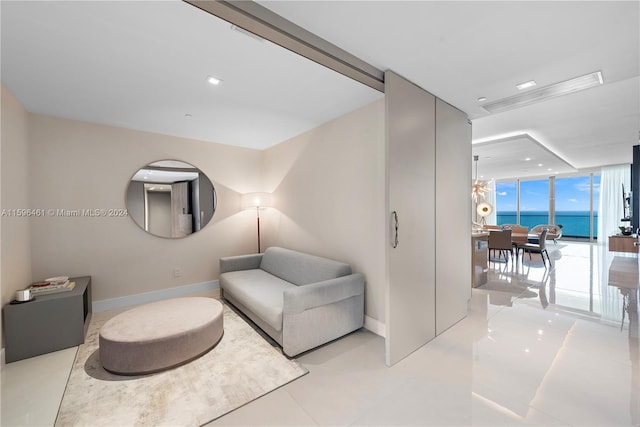 sitting room featuring light tile floors, a water view, and a wall of windows