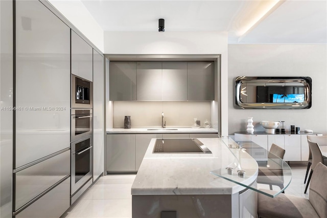 kitchen featuring gray cabinets, stainless steel oven, built in microwave, and cooktop