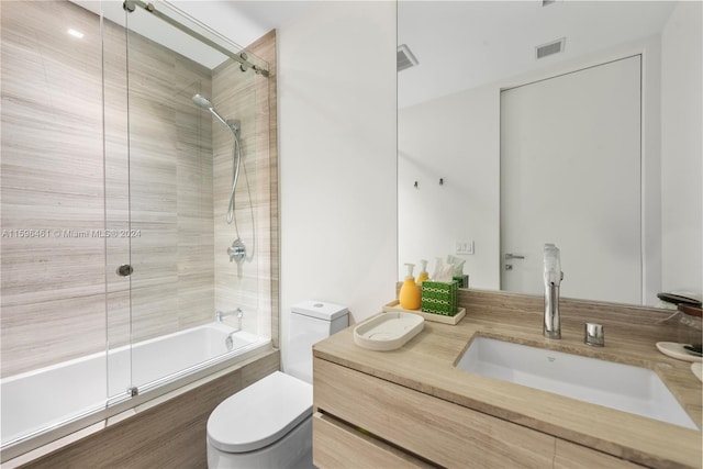 full bathroom featuring tiled shower / bath, vanity, and toilet