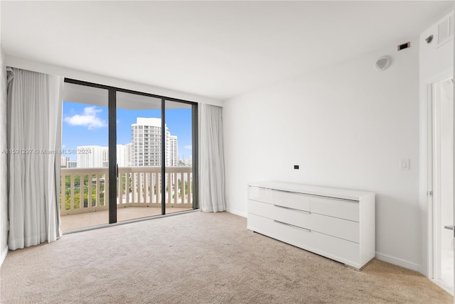 unfurnished bedroom featuring light carpet, a wall of windows, and access to outside