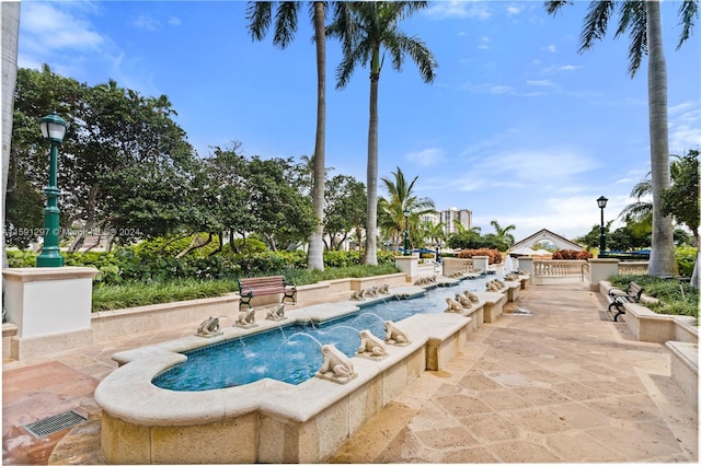 view of swimming pool with pool water feature and a patio