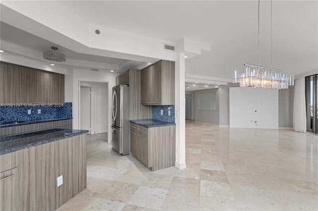 kitchen featuring decorative backsplash, stainless steel refrigerator, and pendant lighting