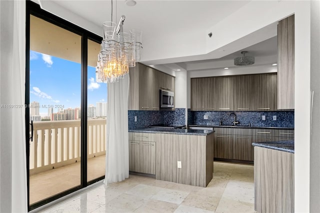 kitchen featuring decorative light fixtures, dark stone countertops, tasteful backsplash, sink, and black electric cooktop