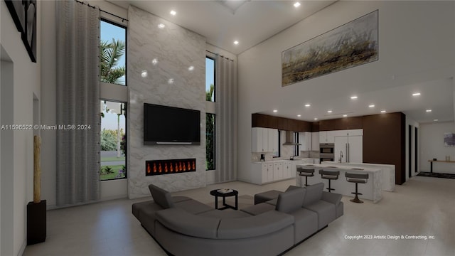 living room featuring a towering ceiling, sink, and a fireplace