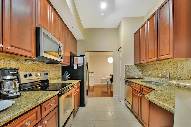 kitchen featuring light stone countertops, tasteful backsplash, light tile flooring, sink, and appliances with stainless steel finishes