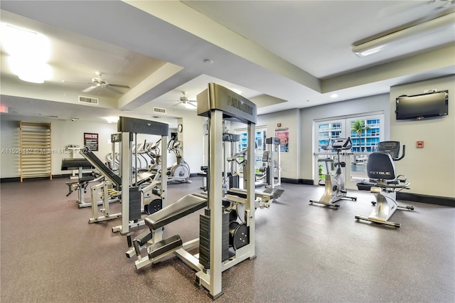 workout area with ceiling fan and a raised ceiling