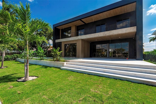 rear view of house with a yard and a balcony