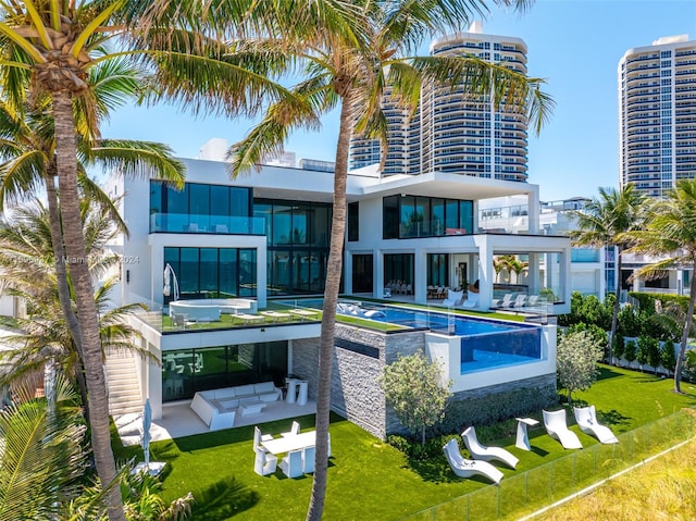 back of property featuring outdoor lounge area, a balcony, and a lawn