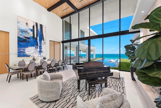 living room with floor to ceiling windows, wooden ceiling, a water view, and a high ceiling