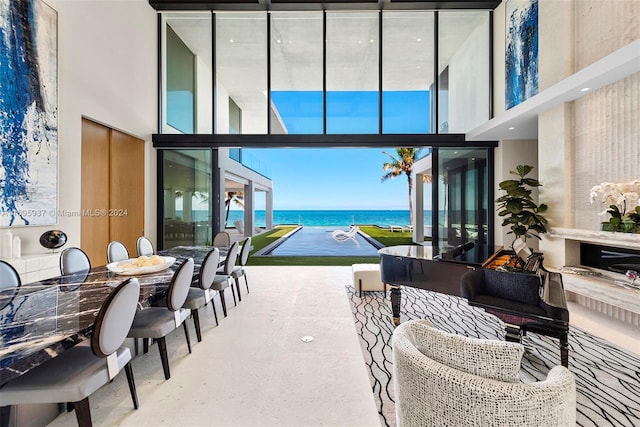 living room with a high ceiling, a wall of windows, and a water view