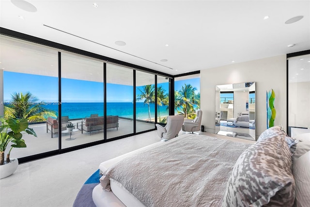 bedroom featuring a wall of windows, a water view, and access to exterior