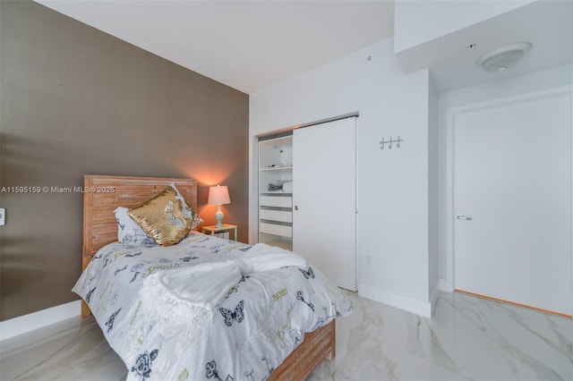 bedroom with a closet, marble finish floor, and baseboards